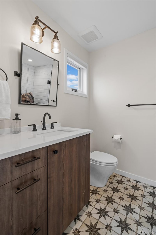 bathroom featuring visible vents, toilet, vanity, baseboards, and tile patterned floors