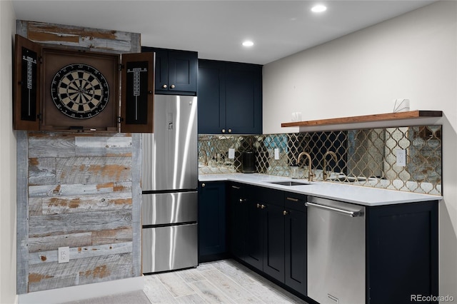 kitchen featuring stainless steel appliances, tasteful backsplash, light countertops, light wood-style floors, and a sink