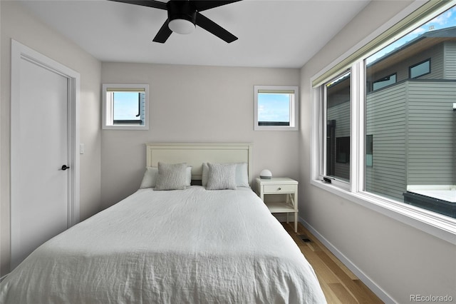 bedroom with visible vents, wood finished floors, a ceiling fan, and baseboards