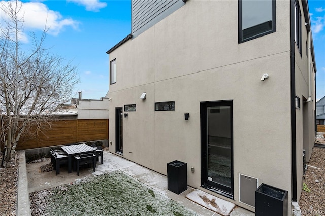 rear view of house with a patio area, fence, and stucco siding