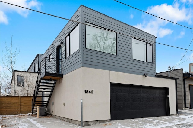 exterior space featuring a garage, stucco siding, central AC, and stairs