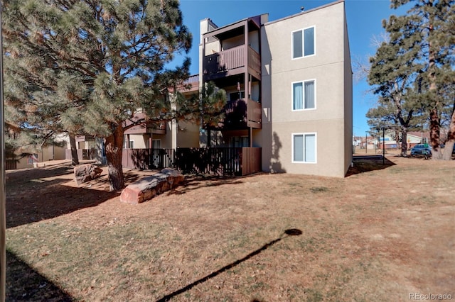 rear view of house with a lawn and stucco siding