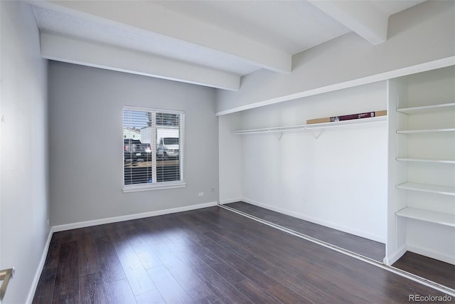 spare room with beamed ceiling, wood finished floors, and baseboards