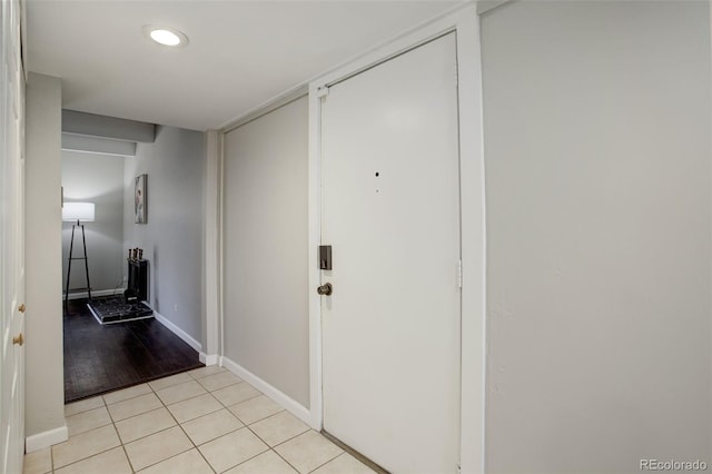 hall featuring light tile patterned floors and baseboards