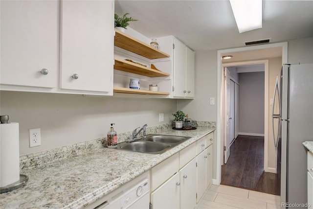 kitchen featuring visible vents, white cabinets, a sink, light countertops, and freestanding refrigerator