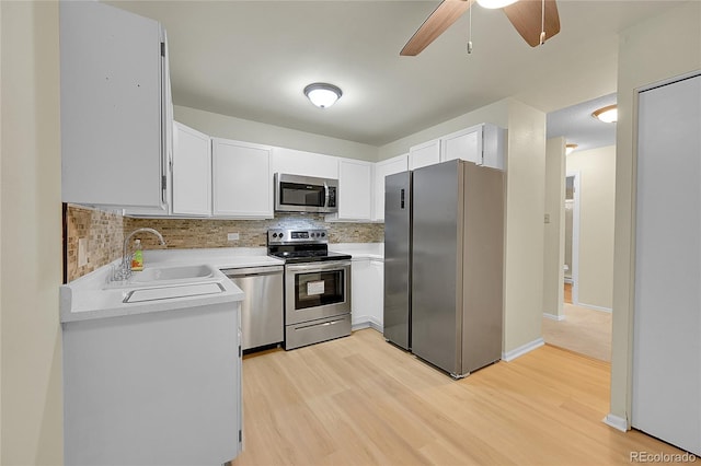 kitchen featuring white cabinets, sink, light wood-type flooring, appliances with stainless steel finishes, and tasteful backsplash