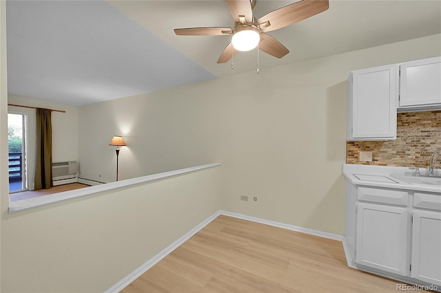 interior space featuring light wood-type flooring, a wall unit AC, ceiling fan, and sink