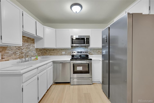 kitchen with backsplash, stainless steel appliances, sink, light hardwood / wood-style flooring, and white cabinetry