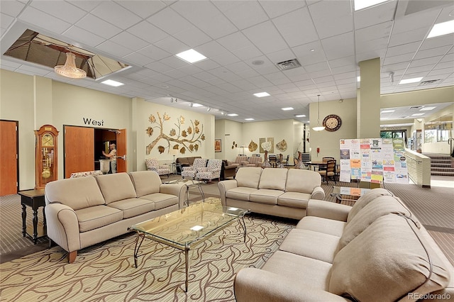 living room with a drop ceiling and light colored carpet