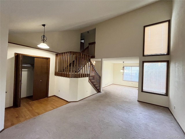 17969 E Brown Pl, Aurora, CO 80013 - unfurnished living room with carpet floors, stairs, a chandelier, baseboards, and high vaulted ceiling