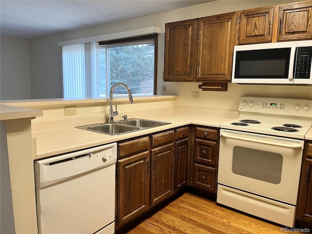 17969 E Brown Pl, Aurora, CO 80013 - kitchen featuring white appliances, a sink, light countertops, light wood-style flooring, and dark brown cabinets