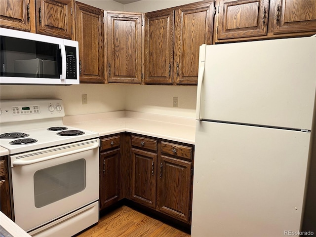 17969 E Brown Pl, Aurora, CO 80013 - kitchen with white appliances, light countertops, light wood finished floors, and dark brown cabinetry