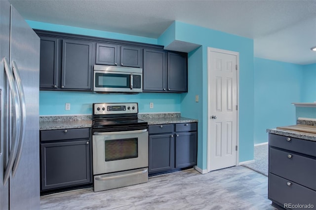 kitchen with light stone counters and appliances with stainless steel finishes