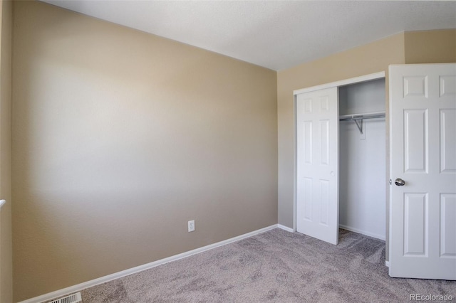 unfurnished bedroom featuring light colored carpet and a closet