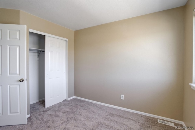 unfurnished bedroom featuring a closet and light carpet