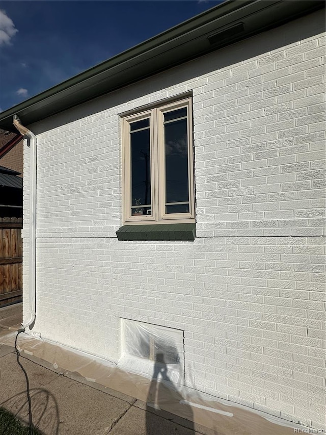 view of side of property featuring fence and brick siding