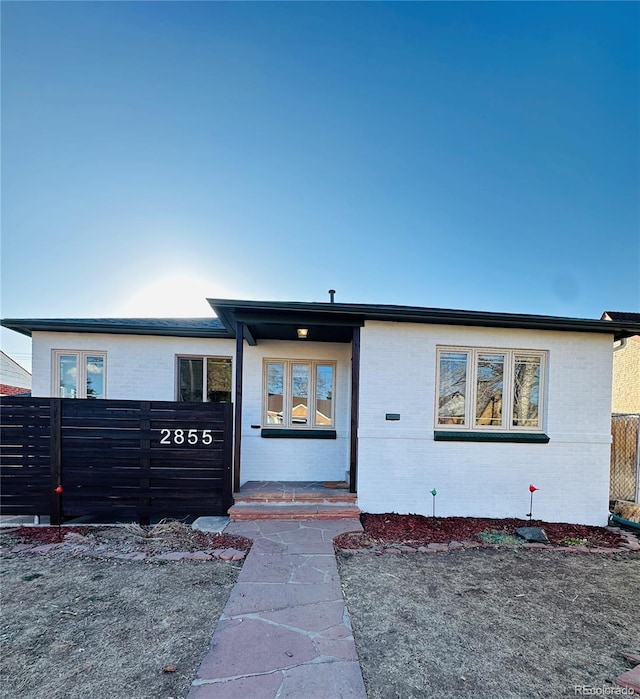 view of front of home with brick siding and fence