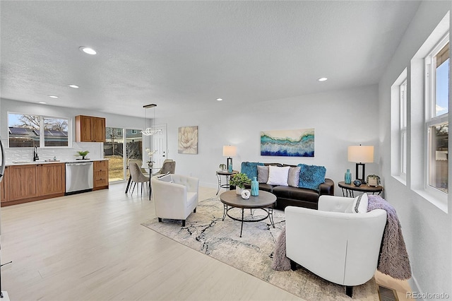 living room featuring sink, a textured ceiling, and light wood-type flooring