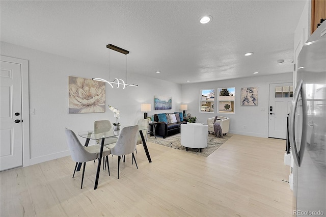 dining area with a textured ceiling and light hardwood / wood-style floors