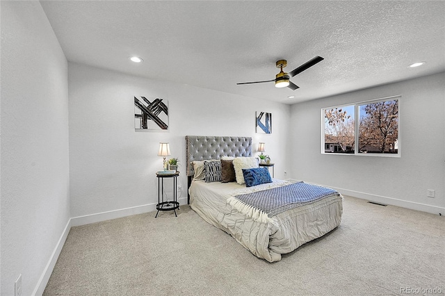 bedroom with ceiling fan, carpet, and a textured ceiling