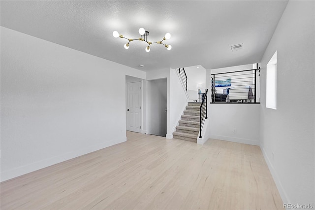 interior space with an inviting chandelier, light hardwood / wood-style floors, and a textured ceiling