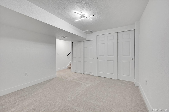 basement featuring light carpet and a textured ceiling