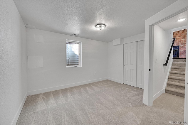 basement featuring light colored carpet and a textured ceiling