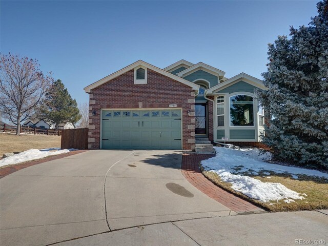 view of front of home with a garage, brick siding, driveway, and fence