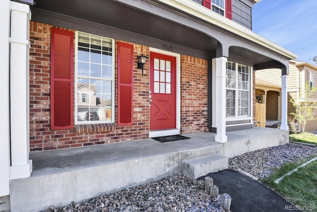 property entrance with covered porch and brick siding