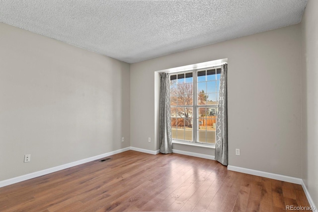 unfurnished room with wood finished floors, baseboards, and a textured ceiling