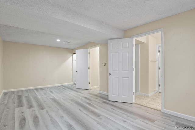 spare room featuring light wood-style flooring, a textured ceiling, baseboards, and recessed lighting