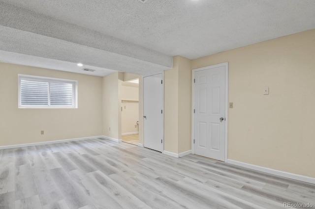 unfurnished room featuring a textured ceiling, light wood-style floors, baseboards, and recessed lighting
