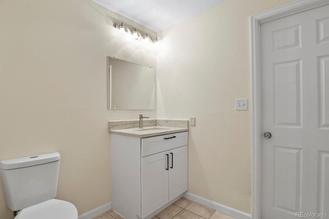 bathroom with baseboards, tile patterned flooring, toilet, and vanity