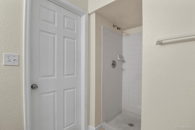full bathroom with a tile shower and a textured wall