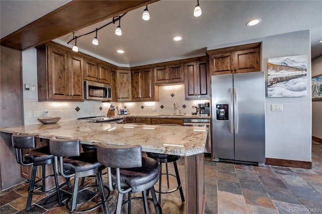 107 Ski Watch Rd Unit 32, Breckenridge, CO 80424 - kitchen with appliances with stainless steel finishes, stone tile floors, a peninsula, light stone counters, and backsplash