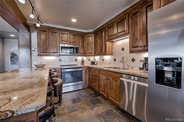 107 Ski Watch Rd Unit 32, Breckenridge, CO 80424 - kitchen featuring appliances with stainless steel finishes, light stone counters, backsplash, dark stone finish floors, and a peninsula
