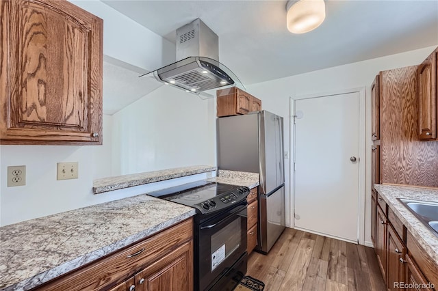 kitchen with island exhaust hood, stainless steel fridge, black range with electric cooktop, and light hardwood / wood-style flooring