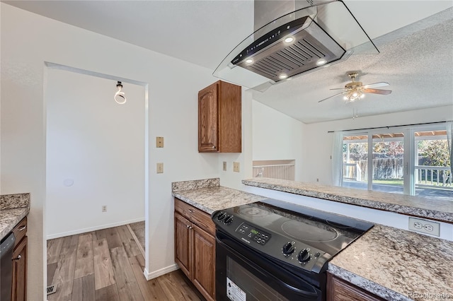 kitchen featuring a textured ceiling, island range hood, ceiling fan, black appliances, and light hardwood / wood-style floors