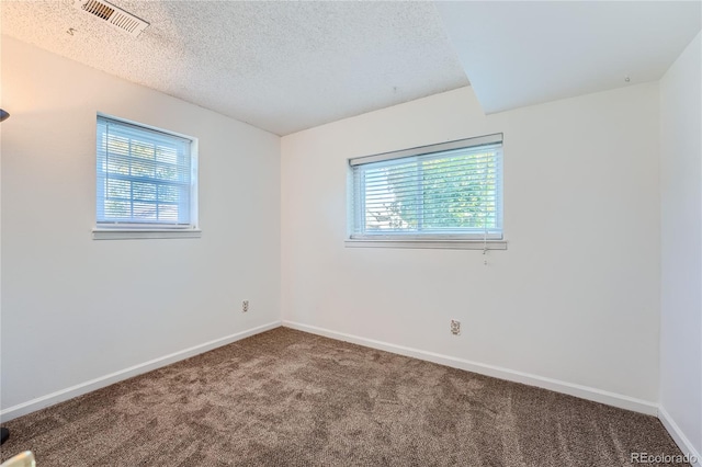 carpeted empty room featuring a textured ceiling