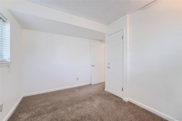 unfurnished room with carpet and a textured ceiling