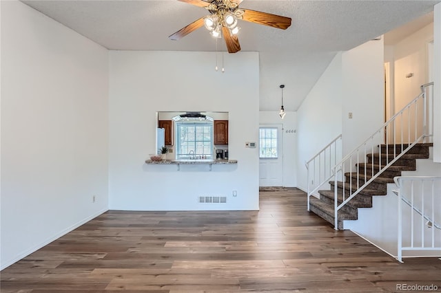 unfurnished living room featuring ceiling fan, sink, dark wood-type flooring, and a textured ceiling