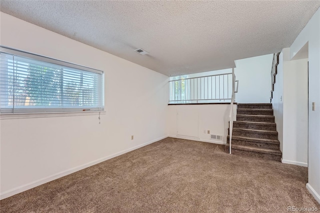 carpeted spare room with a textured ceiling