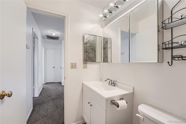 bathroom with vanity, a textured ceiling, and toilet