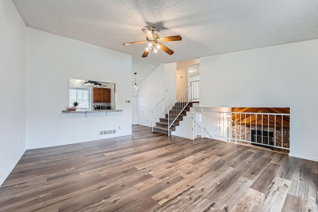 unfurnished living room with ceiling fan, a textured ceiling, and hardwood / wood-style flooring