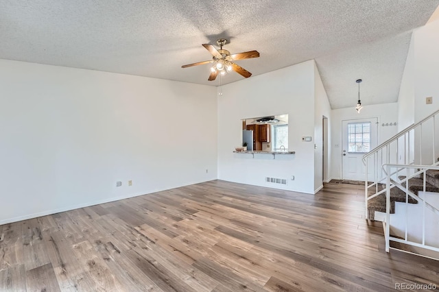 unfurnished living room with hardwood / wood-style floors, ceiling fan, and a textured ceiling