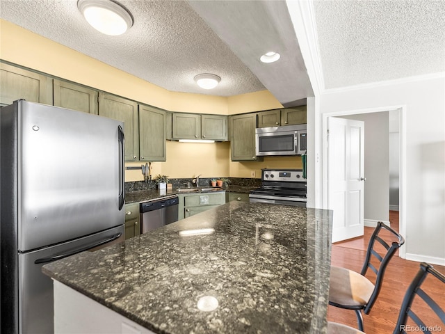 1301 Speer Blvd Unit 702, Denver, CO 80204 - kitchen with appliances with stainless steel finishes, green cabinetry, a textured ceiling, a sink, and dark wood-style floors
