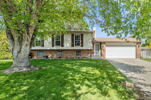 11199 Dahlia Pl, Thornton, CO 80233 - split level home with an attached garage, concrete driveway, a chimney, a front yard, and brick siding