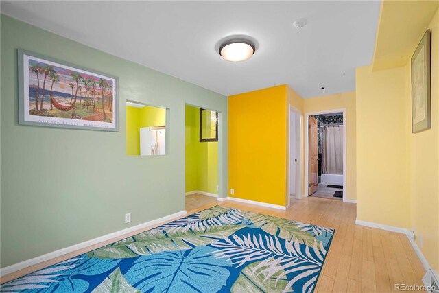 2627 Champa St, Denver, CO 80205 - unfurnished bedroom with white refrigerator with ice dispenser and light wood-type flooring