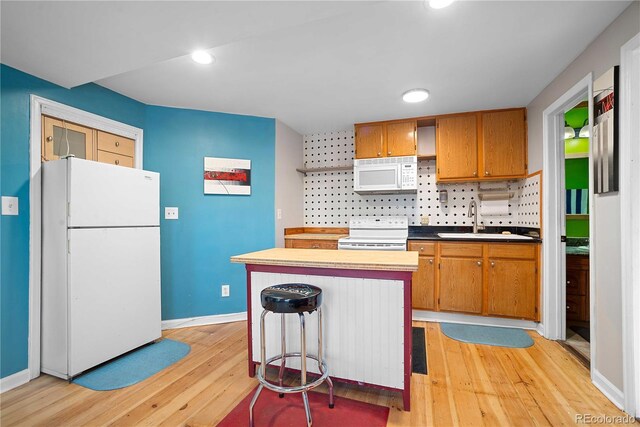 2627 Champa St, Denver, CO 80205 - kitchen featuring white appliances, light wood-style floors, recessed lighting, brown cabinetry, and a center island