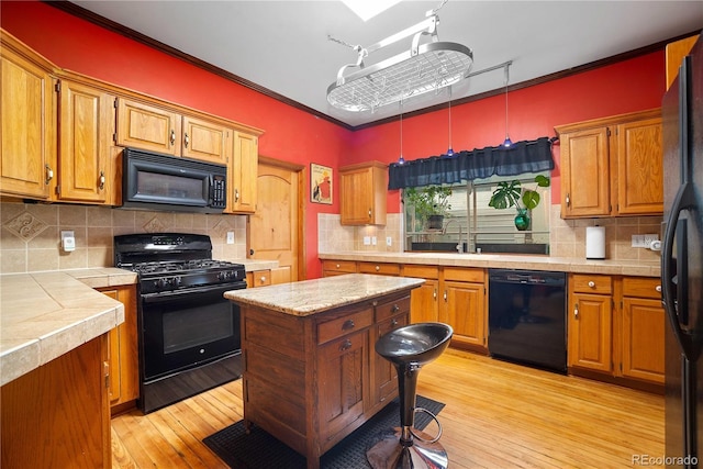 2627 Champa St, Denver, CO 80205 - kitchen featuring black appliances, crown molding, backsplash, light wood-style flooring, and tile countertops